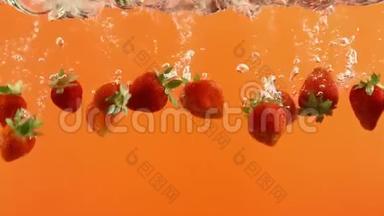 成熟的草莓在橙色背景下<strong>落入水中</strong>。 夏季浆果在液体中